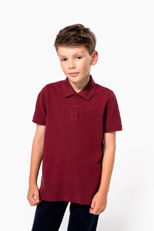 Polo piqué enfant Kariban K2029. 100 % coton bio, grammage 180 g/m². Coupe slim, 2 boutons, sans étiquette. Idéal pour broderie, flocage ou rebranding professionnel. bordeaux
