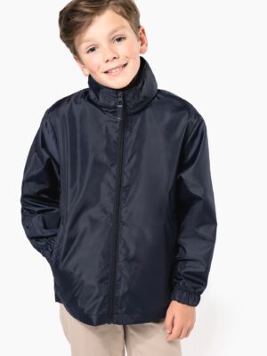 Coupe‑vent enfant Kariban K6102 : 100 % polyester 70 g/m², capuche rangée, poches zippées, se plie dans sa poche. Léger, compact et parfait pour personnalisation textile.noir