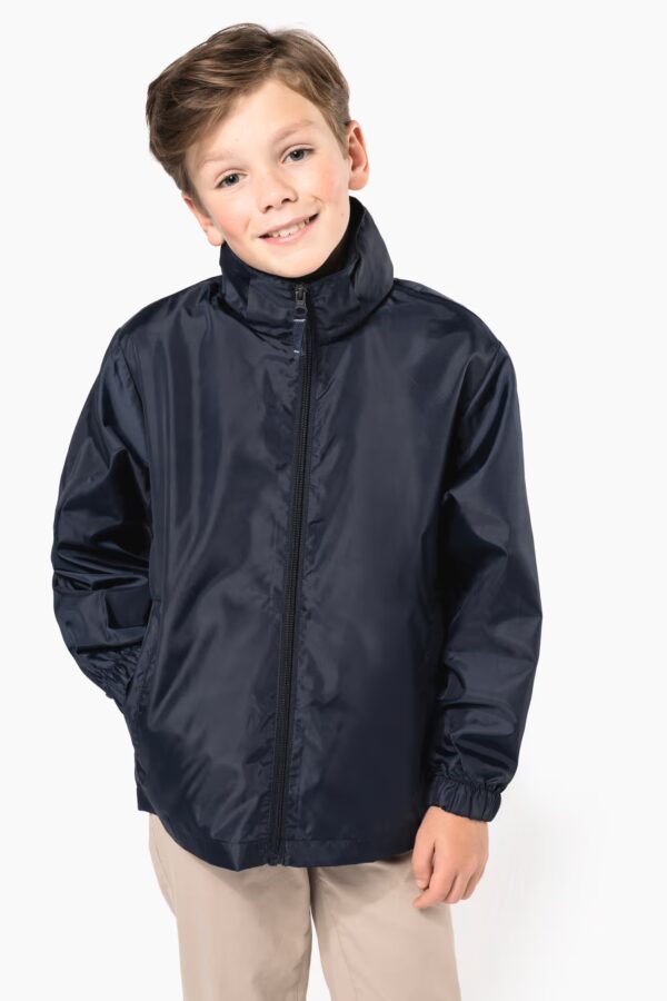 Coupe‑vent enfant Kariban K6102 : 100 % polyester 70 g/m², capuche rangée, poches zippées, se plie dans sa poche. Léger, compact et parfait pour personnalisation textile.noir