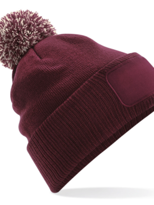 Bonnet B443 avec pompon et patch frontal, chaud et confortable. Idéal pour l’hiver, le merchandising et la personnalisation textile.